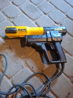 Elektryczna zaciskarka REMS Power Press 230V leżąca na kostce brukowej.