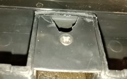Zbliżenie na czarny plastikowy element z wycięciem i śrubą krzyżakową