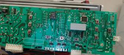 Zbliżenie na płytkę elektroniczną z widocznymi elementami elektronicznymi i wyświetlaczem.