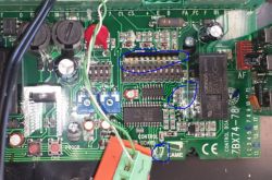 Widok płytki drukowanej z zaznaczonymi uszkodzeniami i komponentami elektronicznymi.