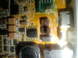 Zbliżenie na uszkodzoną płytkę drukowaną z widocznymi przypalonymi elementami elektronicznymi.