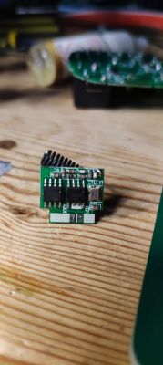 Electronic module with visible components on a wooden surface.