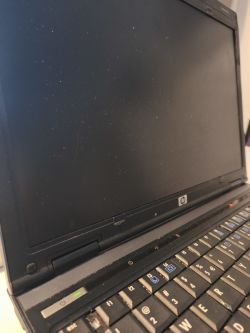 Zamknięty ekran laptopa HP Compaq 6910p z włączonym przyciskiem zasilania