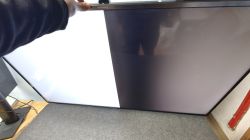 Telewizor z usterką: lewa połowa ekranu biała, prawa przyciemniona; dłoń trzyma górną ramkę