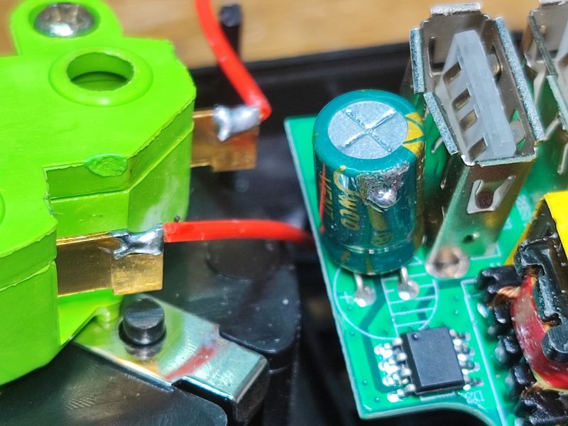 Zbliżenie na wnętrze listwy zasilającej z widocznymi elementami elektronicznymi i lutami.