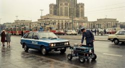 Policeman in uniform examines robotic vehicle on Warsaw street