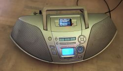 Panasonic boombox with a small LCD screen fitted in the top recess and visible wires hanging down