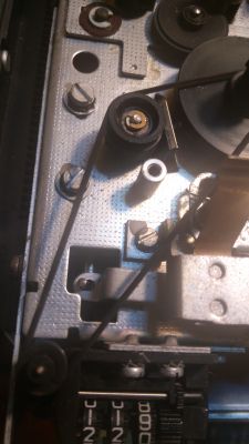 Zbliżenie na wewnętrzną część urządzenia elektronicznego z metalowymi elementami i taśmą.