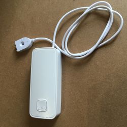 White Water Leak Sensor White water leak sensor with attached cable lying on a wooden surface.