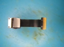 Flexible flat cable (FFC) with gold-plated contacts and mounting clip on a blue surface