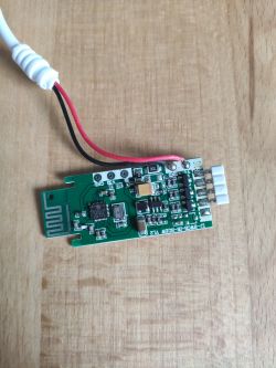 Small printed circuit board with various electronic components on a wooden surface.