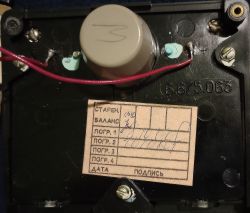 Widok wnętrza urządzenia pomiarowego z etykietą kalibracyjną i elementami elektronicznymi.