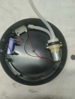 Wnętrze okrągłej obudowy z silniczkiem, wężykami, przewodami i małą płytką elektroniczną