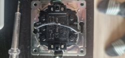Zbliżenie na stary przełącznik elektryczny z widocznymi numerami i przewodami ułożonymi poziomo.