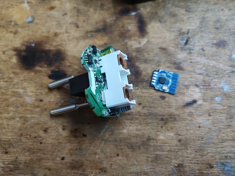 Demontierte Smart-Steckdose mit BK7231M-Modul Demontierte Smart-Steckdose mit BK7231M-Modul auf einem Holztisch.