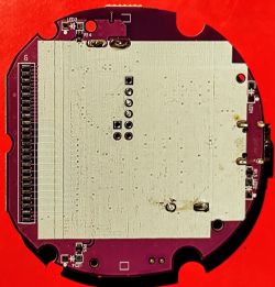 Round PCB on a Red Background Round printed circuit board (PCB) with visible traces and mounting holes, on a red background.
