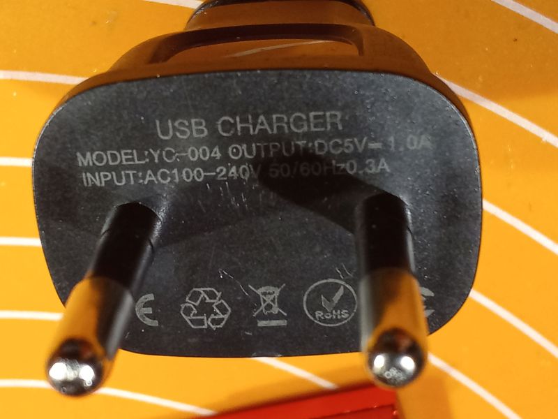 Zbliżenie na wtyczkę ładowarki USB model YC-004 z oznaczeniami technicznymi