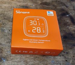 Sonoff SNZB-02D Packaging Sonoff SNZB-02D packaging on a wooden surface.