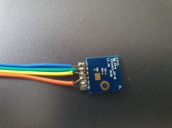 Electronic circuit with attached wires in blue, green, yellow, and orange colors.