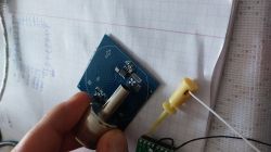 Hotair nozzle heating an electronic component on a blue PCB over graph paper.