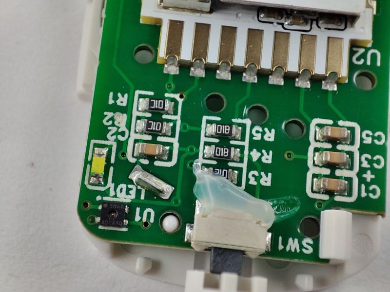 Close-up of a device PCB with SMD components, an LED, and a SW1 switch