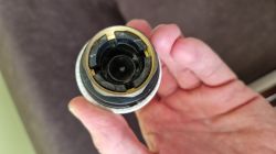 Widok od spodu głowicy termostatycznej Danfoss trzymanej w dłoni, z wyraźnie widocznym mechanizmem mocowania z tworzywa sztucznego i metalu.