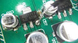 Nahaufnahme einer Leiterplatte mit einem AMS1117-Mikrochip und Kondensatoren.