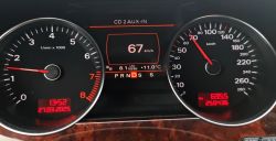 Zbliżenie na zegary samochodu Audi, pokazujące prędkość 67 km/h, przebieg 250436 km i średnie spalanie 8,1 l/100 km.