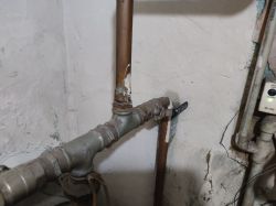 Zużyta instalacja z zaworem kulowym i rurami miedzianymi i stalowymi