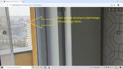 Widok z balkonu na miasto, z widocznym wysokim blokiem ponad 10 pięter.