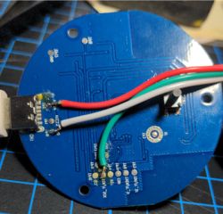 Close-up of the back side of a round printed circuit board with connected wires.