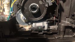 Wnętrze ekspresu do kawy z widocznymi elementami mechanicznymi i śladami wilgoci w okolicach mechanizmu napędowego.
