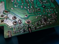 Close-up of a green PCB with solder joints, traces, and several SMD components