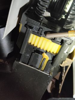 Zbliżenie na mechanizm zaparzacza ekspresu z widocznym wyciekiem przy żółtym kole zębatym