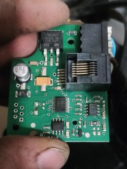 Zbliżenie na zieloną płytkę drukowaną z różnymi podzespołami elektronicznymi.