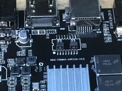 Zbliżenie na płytę główną przystawki TV, widoczne złącza HDMI, WAN oraz układy scalone i radiatory.