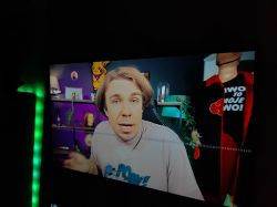 Osoba podczas nagrywania w domowym studio z półkami i dekoracjami w tle.