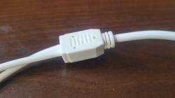 Biały kabel z plastikowym złączem na drewnianym blacie.