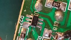 Zbliżenie na układ SMD z sześcioma wyprowadzeniami na zielonej płytce PCB, oznaczony jako D27.