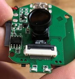 Camera module on PCB with lens and ribbon cable connector visible