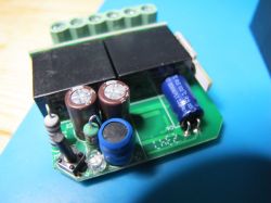 Electronic circuit with capacitors and relays on a green PCB.