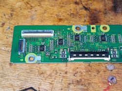 Zbliżenie na płytkę drukowaną z rozmontowanego telewizora plazmowego, ukazującą różne komponenty elektroniczne.