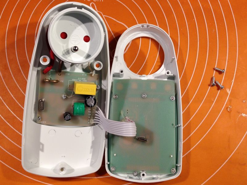 Wnętrze rozebranej obudowy watomierza z widoczną płytką elektroniczną.