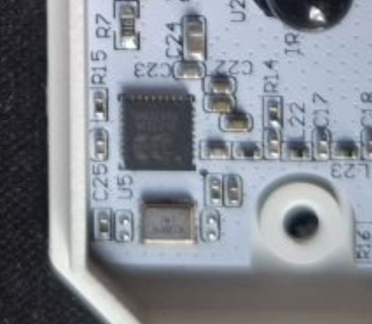 Close-up of a PCB with an IC chip, SMD components, and a mounting hole