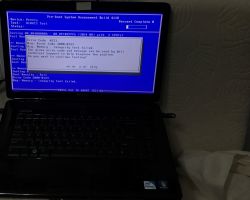 Laptop Dell Inspiron na łóżku z niebieskim ekranem testu pamięci i komunikatem o błędzie
