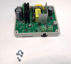 Widoczna otwarta płytka drukowana z elektroniką zamontowana w plastikowej obudowie, obok leżą cztery wkręty.