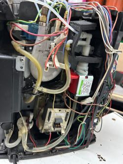 Wnętrze ekspresu do kawy Delonghi z widocznymi przewodami i komponentami