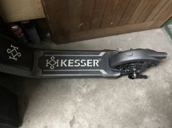Uszkodzona hulajnoga elektryczna KESSER K-ESC-X10 na posadzce garażu.