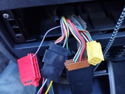 Przewody i kostki w samochodzie Audi A3 podłączone do radia, w tym żółta i czerwona kostka.