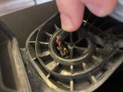 Osoba trzymająca luźny kabel wewnątrz plastikowej obudowy urządzenia.